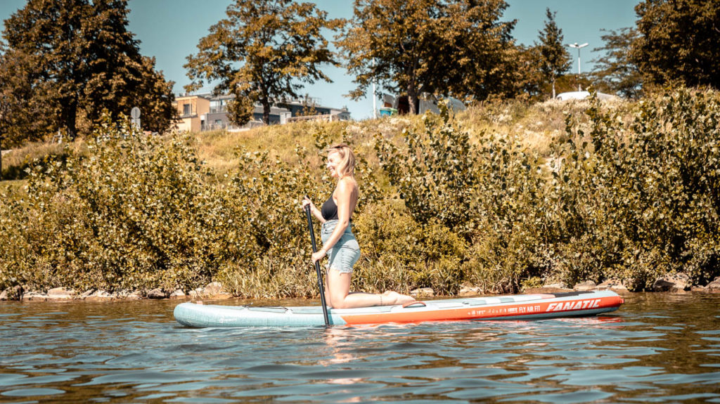 Mädchen kniend am Stand Up Paddle Board auf der Neuen Donau